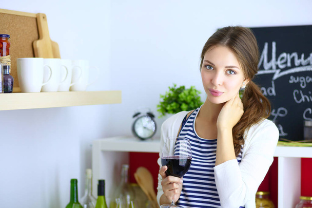 Jolie femme buvant du vin à la maison dans la cuisine - Photo, image