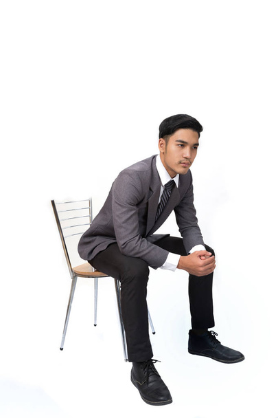 Επιχειρηματίας φορώντας γκρι κοστούμι κάθεται σε καρέκλα και σκέψης πάνω από - Φωτογραφία, εικόνα