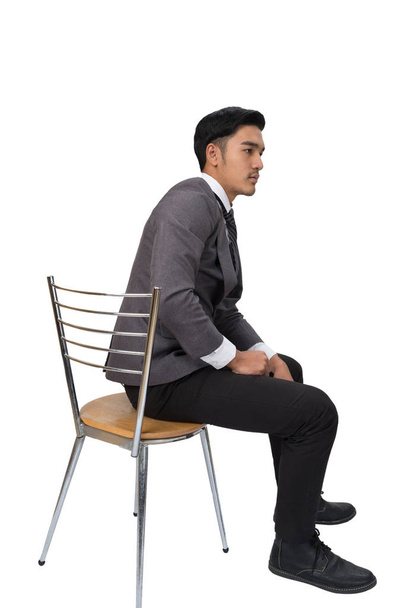 Επιχειρηματίας φορώντας γκρι κοστούμι κάθεται σε καρέκλα και σκέψης πάνω από - Φωτογραφία, εικόνα