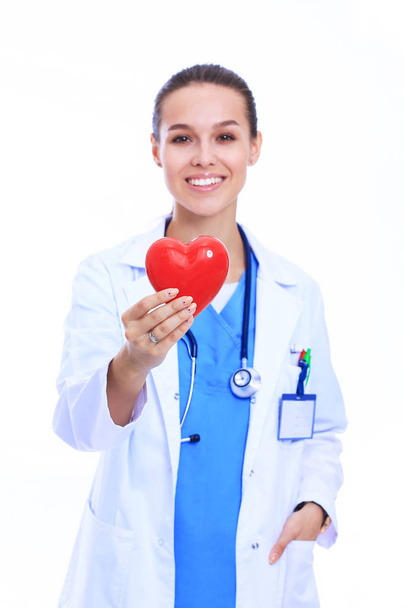 Positive female doctor standing with stethoscope and red heart symbol - Фото, зображення