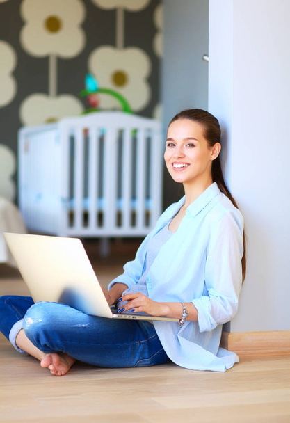 Young beautiful woman at home sitting on the floor with laptop - Фото, зображення