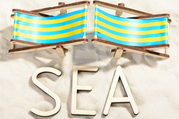 The word SEA and two sunbeds at the beach - Photo, Image