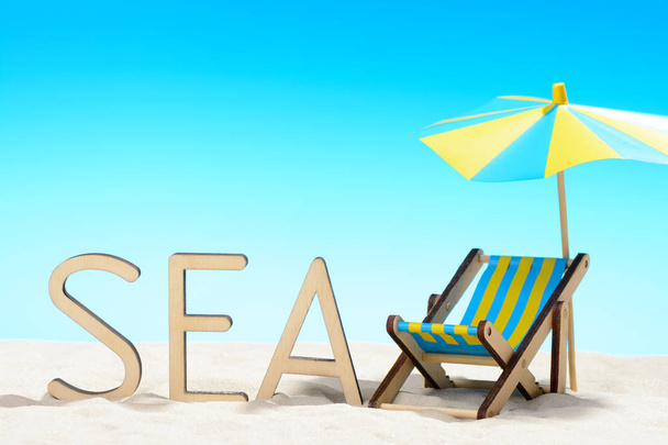 The word SEA and sunbed at the beach on background of blue sky - Photo, Image