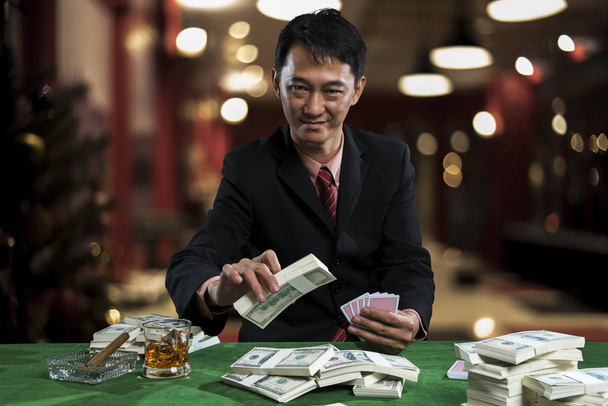 Il giovane giocatore d'azzardo sta scommettendo sui mucchi di banconote.
 - Foto, immagini