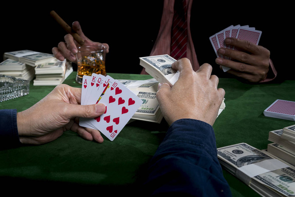 The gambler is putting bets into the piles of banknote and holdi - Fotografie, Obrázek