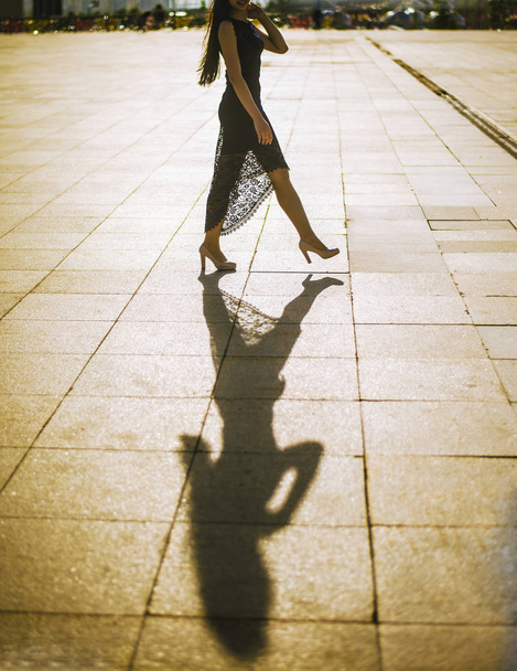 Young fashion woman  in the black dress walking to stoned pathway - Foto, imagen