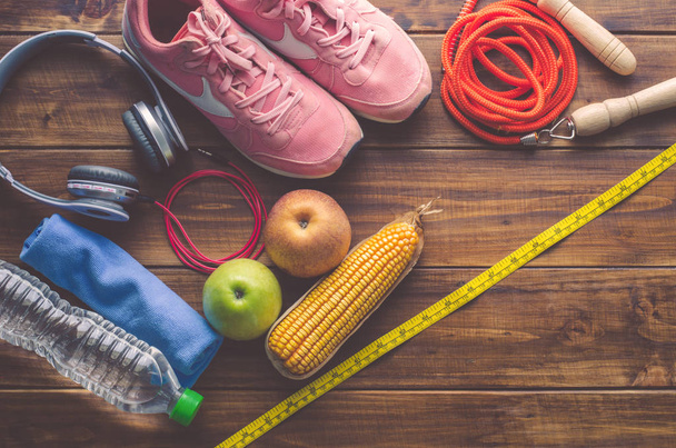 Koncepcja fitness ze sprzętem do ćwiczeń oraz zdrowe jedzenie na podłoże drewniane. - Zdjęcie, obraz