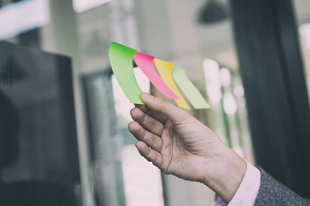 business person hand holding blank sticky paper note on window i - Photo, image