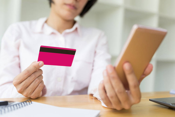 Τα χέρια της γυναίκας κρατώντας μια πιστωτική κάρτα για πληρωμή και χρησιμοποιώντας έξυπνες  - Φωτογραφία, εικόνα