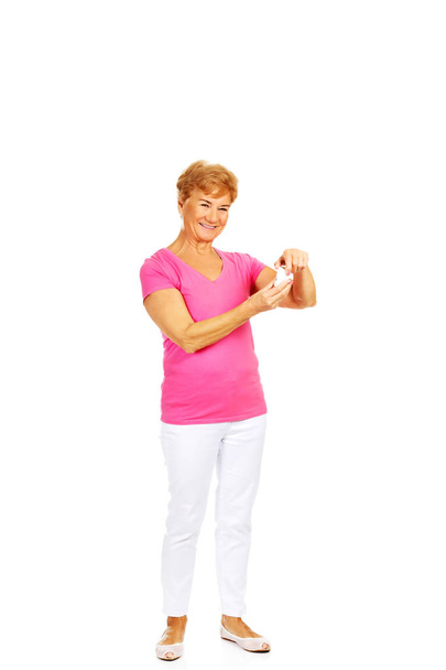 Smiling senior woman holding jar of pills - Zdjęcie, obraz