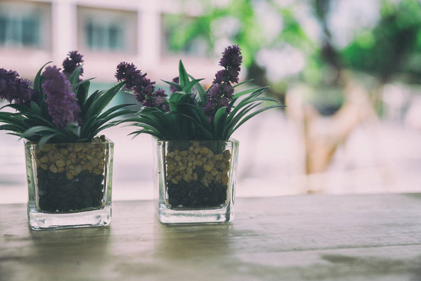 kunstmatige bloem in kleine glazen pot op een houten tafel. - Foto, afbeelding
