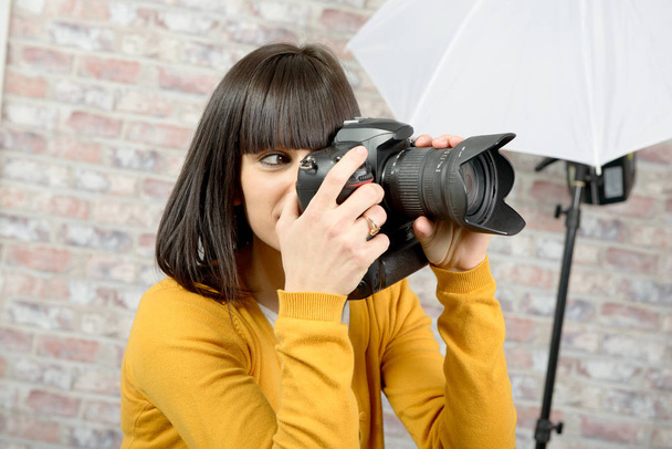 Attraente donna bruna con macchina fotografica in studio
 - Foto, immagini