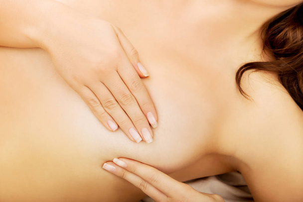 Woman examining her breast in bed. - Foto, Imagen