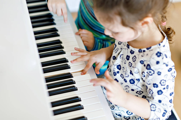 Kaksi pientä lasta tyttö ja poika soittaa pianoa olohuoneessa tai musiikkikoulussa
 - Valokuva, kuva