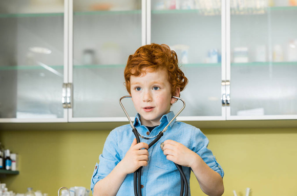 jongen met stethoscoop bij kliniek - Foto, afbeelding