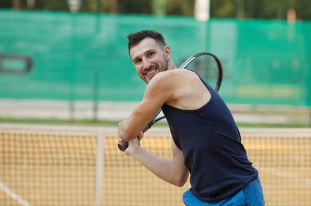 Happy young man playing on tennis clay court. - Valokuva, kuva