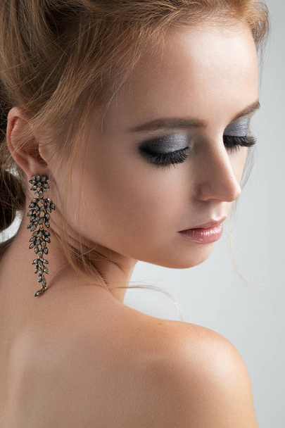 Closeup portrait of blondes with long earrings with closed eyes and silvery eyeshadows. - Fotó, kép