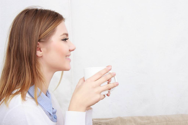 woman sitting on couch in her living room and drinking coffee - Φωτογραφία, εικόνα