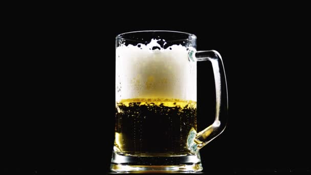 Bier ergießt sich in ein Glas auf schwarzem Hintergrund. Zeitlupe - Filmmaterial, Video
