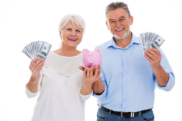 Senior couple holding money and piggy bank - Фото, изображение