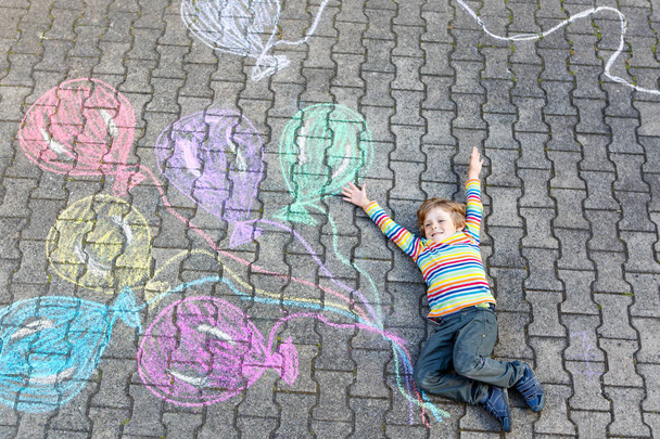 Niño divirtiéndose con globos de colores dibujando con tiza
 - Foto, Imagen
