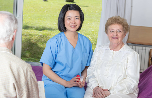 Pielęgniarka, mowie ze starszą kobietę w łóżku szpitalnym - Zdjęcie, obraz