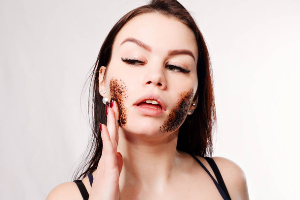 Brunette cleanses the skin with coffee scrub - Foto, imagen