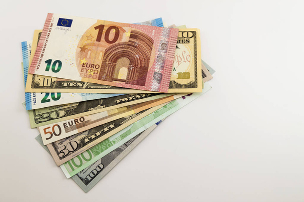 Ons dollarbiljetten en Euro rekeningen verspreiden gemengde op witte achtergrond. - Foto, afbeelding