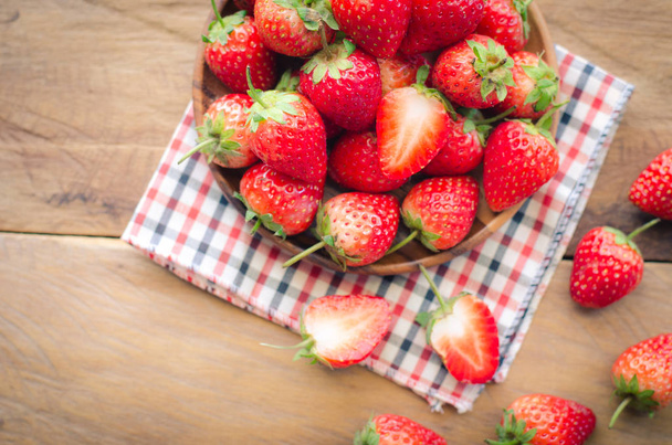 Fresh strawberries in a bowl on wooden background. - Foto, imagen
