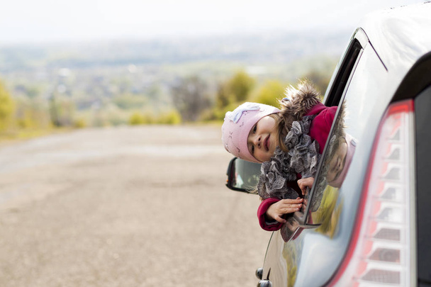 Bella ragazzina in macchina che guarda attraverso il finestrino dell'auto. Viaggio
 - Foto, immagini