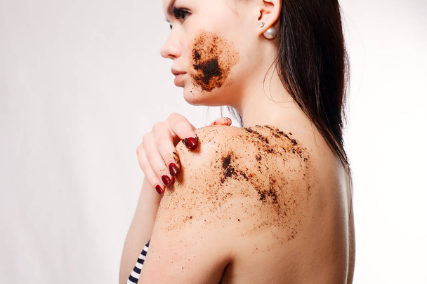 Brunette woman cleans the skin of the body coffee scrub - Foto, imagen