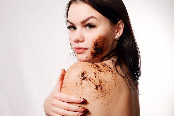 Brunette woman cleans the skin of the body coffee scrub - Foto, immagini