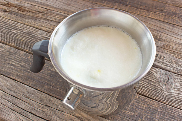 Alarm ahşap tabl ıslık ile metal tencerede sıcak süt haşlanmış - Fotoğraf, Görsel