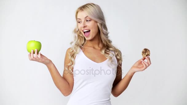 happy young woman with green apple and cookie - Imágenes, Vídeo