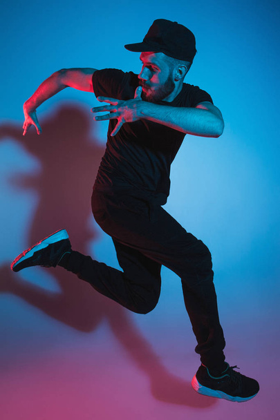 The silhouette of one hip hop male break dancer dancing on colorful background - Фото, зображення