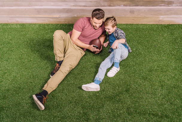 father with son laying on grass - Foto, afbeelding
