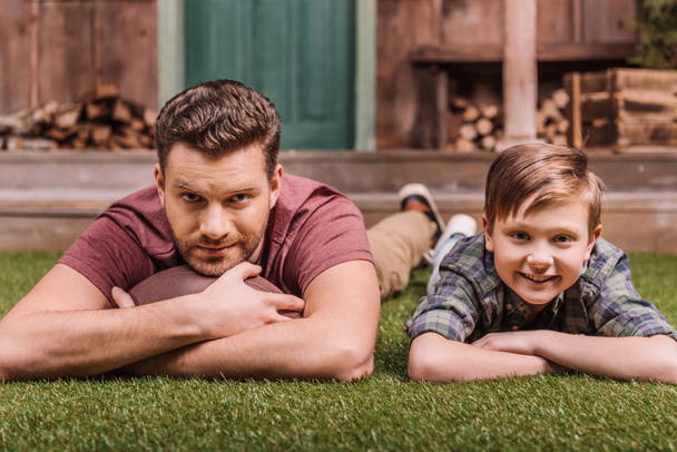 Отец с сыном, лежащим на траве
 - Фото, изображение