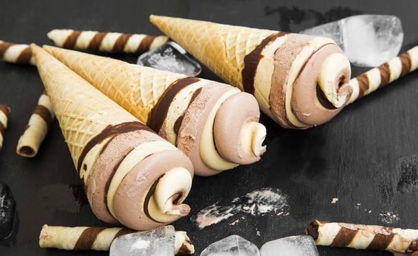 Σοκολάτα και καραμέλα παγωτό κρεμώδη σπείρες σε κώνους βαφλών  - Φωτογραφία, εικόνα