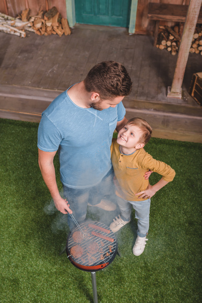 vader en zoon op barbecue - Foto, afbeelding
