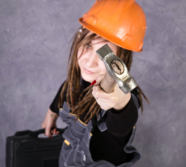 girl in safety helmet orange vest holding hammer tool - Фото, зображення