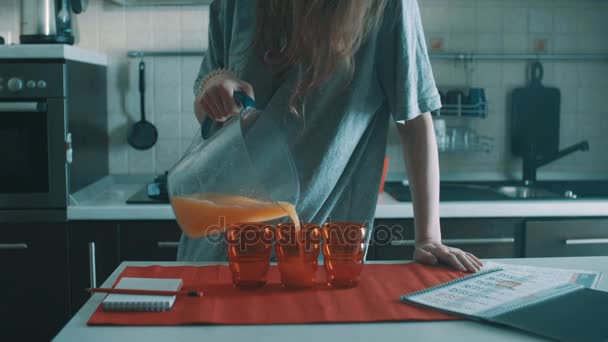 tollpatschiges brünettes Mädchen gießt Orangensaft in rotes Glas und verschüttet es überall - Filmmaterial, Video