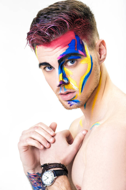 portrait of young attractive man with colored face paint on white background. Professional Makeup Fashion. ffantasy art makeup - Photo, image