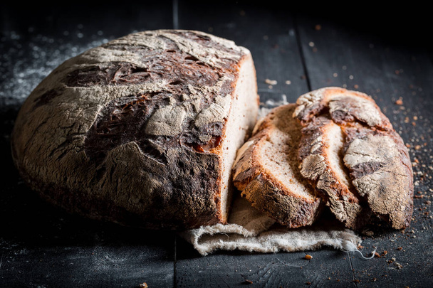 Healthy sliced loaf of bread for breakfast on dark table - Photo, Image