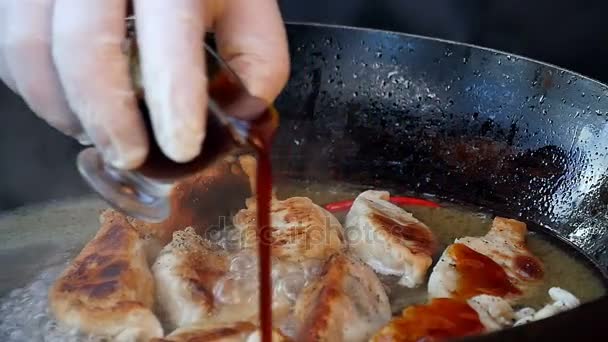 Pouring sauce over fried dumplings in pan - Footage, Video