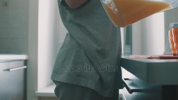 Vista lateral da jovem garota derramando suco de jarro em vidro, derrama-o na mesa
 - Filmagem, Vídeo