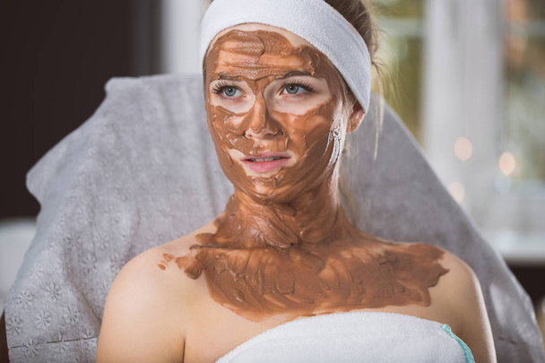 Young woman during refreshing chocolate mask treatment in spa - Photo, Image
