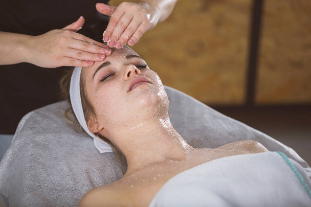 Mujer joven durante la terapia de exfoliación con sal facial
 - Foto, imagen