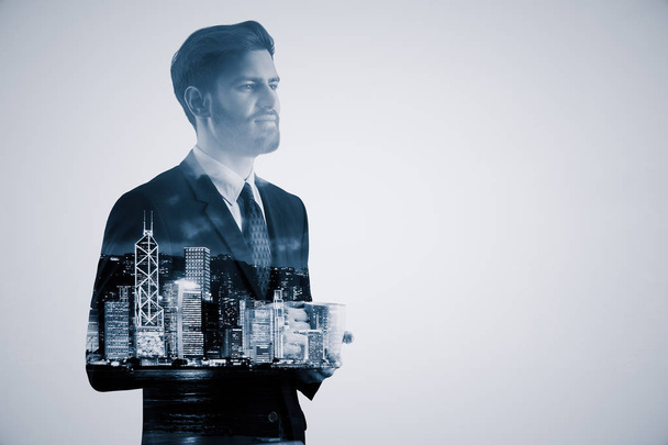 Handsome thoughtful young businessman drinking coffee on abstract night city background. Career concept. Double exposure - Photo, image