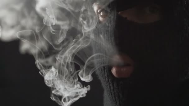gevaarlijke terrorist in een balaclava vape van de e-sigaret rookt en maakt een heleboel rook. - Video