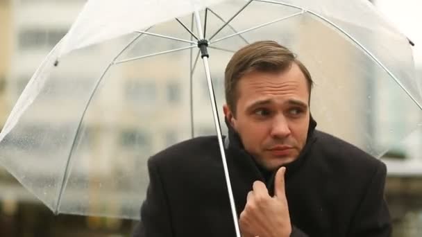 Frustrated by the weather, standing under the umbrella during the rain. Unhappy man in a suit - Filmati, video